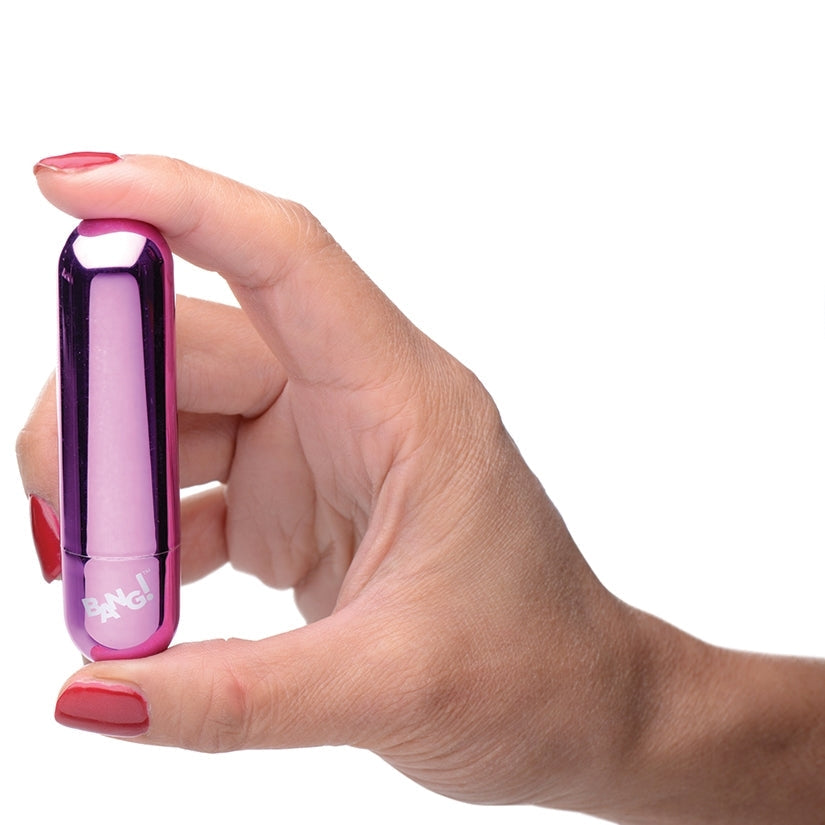 Hand holding a small purple and pink device with a white background